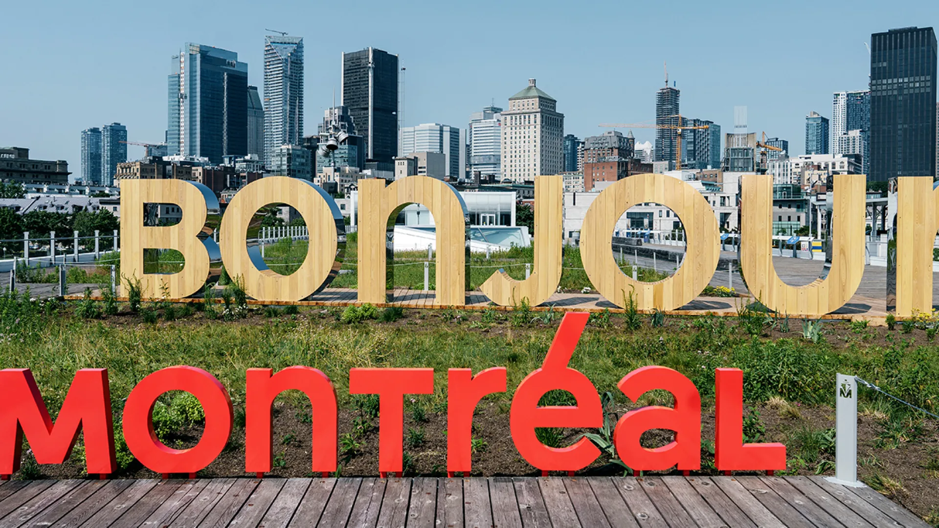 City Of Montreal day time skyline. The words Tourisme/ Montréal/Montre’al written over it. The word bonjour appears made of pine in foreground